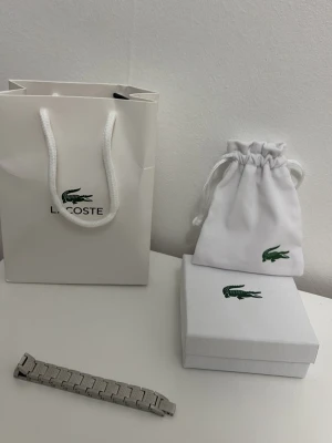 Lacoste armband  - Ett Lacoste armband helt oanvänd. Perfekt om man vill höja sin outfit till nästa nivå. Be om fler bilder och fråga om du undrar över något kommer även med en sak du kan justera storleken med på armbandet. Priset kan diskuteras.