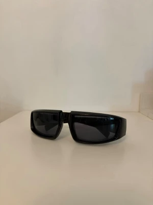 Svarta chunky solglasögon - Säljer ett par chunky svarta solglasögon med bred båge och rektangulära glas. De har en modern och edgy vibe, perfekta för dig som vill sticka ut. Glasen är mörka och bågarna är i blank plast.
