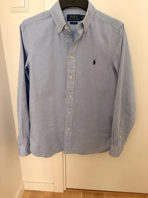Ljusblå skjorta från Polo Ralph Lauren - Klassisk ljusblå skjorta från Polo Ralph Lauren. Skjortan är köpt från KidsBrandStore för 1500kr och är amvänd två gånger 