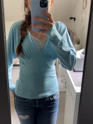 Ljusblå långärmad topp med v-ringning - Säljer en ljusblå långärmad topp med v-ringning. Säljer för att den är lite stor i axlarna. Helt ny från Gina tricot med lappar kvar ☺️💕