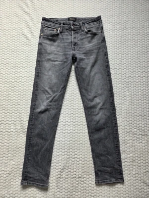 Jeans från Jack & Jones - Säljer dessa gråa jeans från Jack & Jones med slim fit som passform och W29/L32 i storlek. Klassiska 4 fickor med en 5:te minificka. De är inte överdrivet slitna och ser fortfarande fantastiska ut på. Inga stora skador eller liknade. Dessa är nu för små för mig och därför säljer jag dem. Pris kan självklart diskuteras!