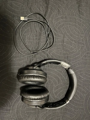 Svarta over-ear hörlurar från Sony - Snygga svarta over-ear hörlurar från Sony med vadderade kåpor och justerbart huvudband. Hörlurarna har inbyggda knappar på sidan och kommer med en USB-laddningskabel. Perfekta för musik, gaming eller filmkvällar.