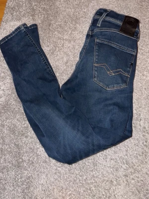 Mörkblå jeans från Replay - Snygga mörkblå jeans från Replay med klassisk femficksmodell och slitna detaljer framtill. Jeansen har raka ben och kontrastsömmar samt en läderpatch bak i midjan. Perfekta för en avslappnad och trendig look. Ny pris 1799, Säljer för 849 WAIST 28,    LENGHT 32