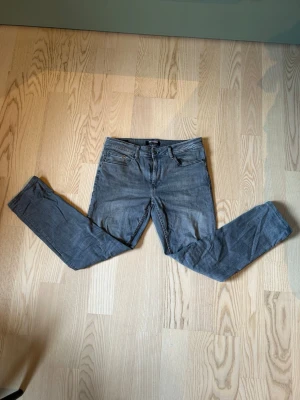 Grå slim fit jeans från Gina Tricot - Säljer ett par grå slim fit jeans från Only & Sons med klassisk femficksdesign och dragkedjegylf. Jeansen har en snygg tvättad look och smala ben som sitter tajt hela vägen ner. Perfekta till en avslappnad och trendig stil.