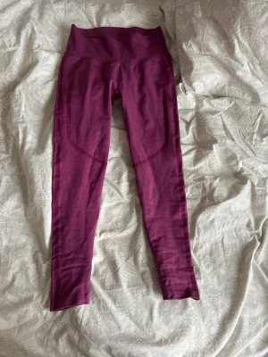 ICIW träningsbyxor  - Säljer ett par typ lila/ vinröda seamless tights med hög midja och scrunch-detalj bak. Tightsen är stretchiga och sitter tight, perfekta för gymmet eller löpning. Materialet är mjukt och följsamt, troligen en blandning av syntetfibrer för maximal komfort. Använda 1 gång, priset går att diskutera 