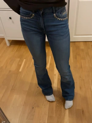 Blå Bootcut Jeans Midrise - Säljer mina Blåa jeans från Lindex i modellen ”Karen” i strl 34 med nitar som jag har satt på💕 Säljer då de inte kommer till användning. Se mått på bild 6. Köpta för 499kr🌟 Skriv vid frågor! Pris kan diskuteras vid snabb affär💫