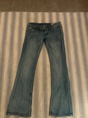 Blå bootcut jeans från diesel - Säljer ett par ljusblå bootcut jeans från diesel med klassisk femficksdesign och låg midja. Skriv för mått