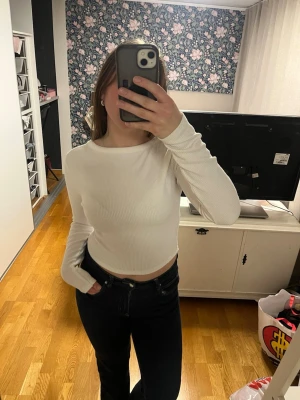 Vit ribbad Långarmad topp - Säljer en vit ribbad croppad topp med långa ärmar. Toppen går att använda åt två håll, antingen med en urringning eller en hög halsl. Perfekt till jeans eller kjol för en clean och enkel look.