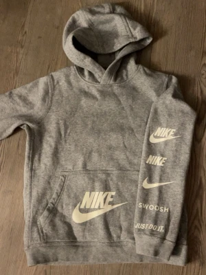 Grå Nike hoodie - Snygg grå hoodie från Nike med flera vita loggor. Klassisk känguruficka framtill och huva. Avslappnad och bekväm 💓