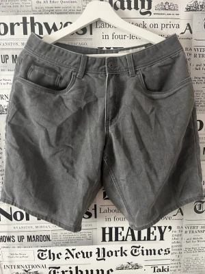 Gråa casual shorts från Livergy - Säljer ett par gråa casual shorts från Livergy i storlek 48. De har klassisk femficksdesign, knapp och dragkedja framtill samt bälteshällor. Perfekta för en avslappnad stil under varmare dagar. Se måttet på bilderna 