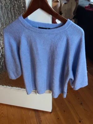 Ljusblå stickad kortärmad tröja -  en ljusblå tunn stickad tröja med korta ärmar. 