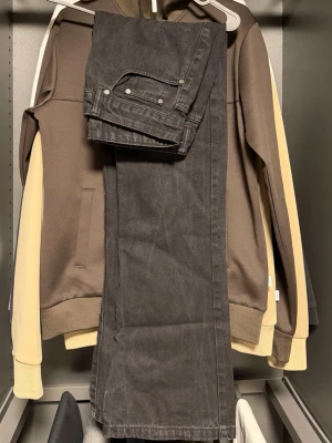 Svarta raka jeans - Säljer ett par svarta jeans med rak passform och klassiska fem fickor. Jeansen har en enkel design utan synliga loggor och är tillverkade i ett kraftigt denimtyg. Perfekta för en stilren och avslappnad look.