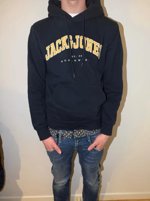Mörkblå Jack&Jones hoodie strl S  - Mörkblå Jack & Jones hoodie i storlek S stilren, bekväm och lättmatchad. Tillverkad i mjukt och skönt material som sitter bra på kroppen utan att kännas tajt. Perfekt både till vardags och chill. Klassisk design med huva och ficka framtill funkar året runt