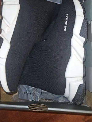 Balenciaga Speed Trainer svarta sneakers - Svarta Balenciaga Speed Trainer sneakers med vit chunky sula och stickad ovandel i textil. Strömlinjeformad design utan snörning och tydlig logga på sidan. Perfekta för en modern och sportig look.