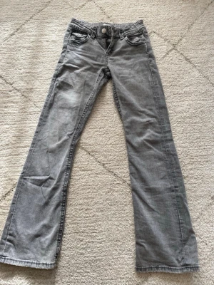 Grå bootcut jeans - Säljer ett par grå bootcut från Gina Tricot. Storlek 158 men passar också som XS. Använda några gånger så skicket är mycket bra. Fin detalj på bakfickan. Perfekta för dig som gillar en avslappnad stil.