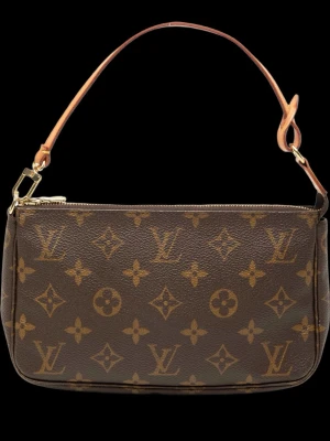 Louis Vuitton Monogram axelremsväska - Klassisk handväska från Louis Vuitton i brunt monogrammönstrat canvas med beige axelrem i läder. Väskan har guldfärgade metalldetaljer och dragkedja upptill. Perfekt storlek för det viktigaste och en ikonisk accessoar för alla tillfällen. Är i mycket bra skick och äkthetsbevis finns. Tillkommer även ett guldkedjeband som jag köpt till från merchofsweden som gör väsksn ännu mer lyxig.