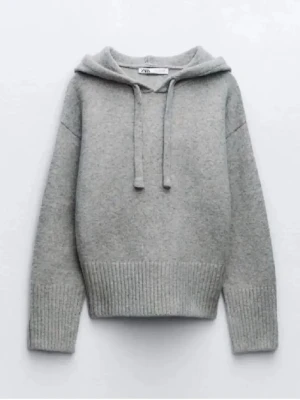 Grå stickad hoodie från Zara - Mysig grå stickad hoodie från Zara med huva och dragsko. Tröjan har ribbade muddar vid ärmslut och nederkant samt en avslappnad passform. Perfekt för en chill och stilren look.