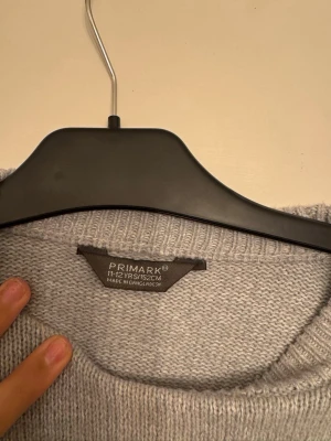 Gråvit randig stickad tröja Primark - Snygg stickad tröja från Primark i ljusgrått med vita horisontella ränder. Tröjan har rund halsringning, långa ärmar och ribbstickade muddar vid ärmslut och nederkant. Perfekt för en chill och stilren look.