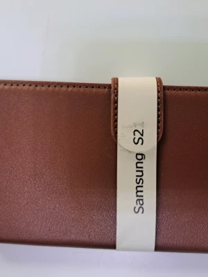 Brunt plånboksfodral Samsung S21 - Snyggt brunt plånboksfodral till Samsung S21. Fodralet är gjort i konstläder och har plats för kort på insidan. Praktisk magnetstängning och öppning för kameran på baksidan. Perfekt för dig som vill skydda mobilen med stil. Jätte snygg för 50 kr