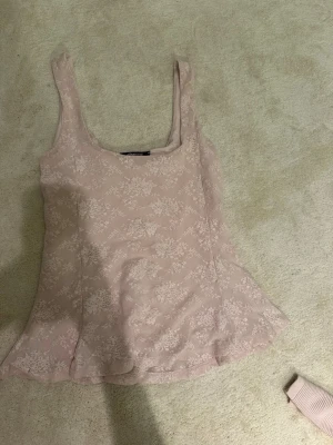 Ljusrosa blommig topp Gina Tricot - Säljer en ljusrosa linnetopp från Gina Tricot med blommigt mönster. Toppen är ärmlös och har en lätt utsvängd passform. Materialet känns mjukt och har ett tunt lager spets ovanpå. Perfekt för dig som gillar romantisk stil! Skriv för frågor osv🥰