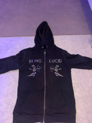Svart hoodie BLING LUCID med strass - Svart hoodie med dragkedja från BLING LUCID. Alla diamanter är kvar säljer den nu pågrund av att den aldrig används nå med skriv för mer info eller bilder! 