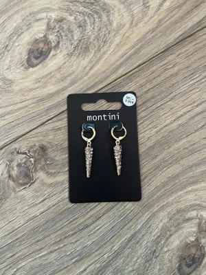 Guldiga örhängen med strass från Montini - Snygga örhängen från Montini i guldfärg med droppformade hängen täckta av glittrande strass. Helt nya och oanvända.