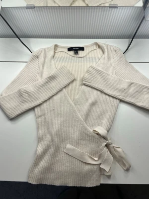 Beige omlottstickad tröja Vero Moda - Snygg beige stickad omlott-tröja från Vero Moda med ribbad struktur och knytband i midjan. Endast lite använd. Bara att höra av dig vid frågor/funderingar!💗💗