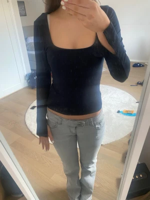 Mörkblå långärmad topp - Säljer en mörkblå långärmad topp med fyrkantig ringning. Toppen är tight i modellen och har en enkel, stilren design utan synliga detaljer. Perfekt att matcha med jeans eller kjol för en clean look. Det är slits på ärmarna