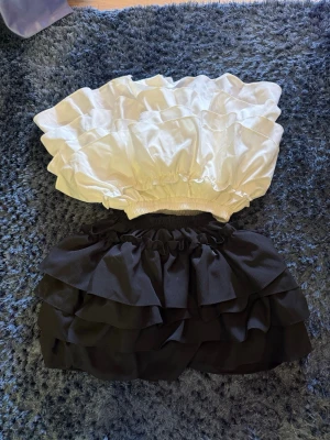 Svart och vit volang bodyset - Säljer 2 stycken riktigt snygga kjolar, båda poffiga med volanger och perfekta för sommaren! Kan sänka pris vid snabb affär.