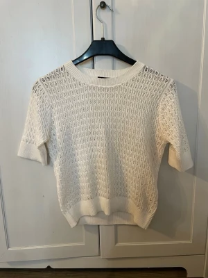 Vit stickad kortärmad tröja - Snygg vit stickad tröja med korta ärmar och rund hals. Säljer tröjan då jag har en likadan och inte får användning för båda. Köpt från lager 157 och är knappast använd. Säljer för 80kr, OBS! Köparen står för frakt