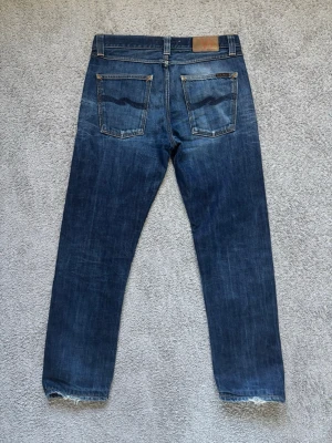 Nudie jeans - Tja, säljer ett par tvär feta nudie jeans med grymm tvätt, storleken på jeansen är 31/34 men är uppsydda så är 31/30. Moddelen är 178 och det sitter perfekt. Mått: midja 42cm, totallängd 100cm, benöppning 19cm. Skriv vid minsta lilla och pris går givetvis att diskutera