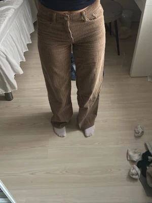 Bruna raka manchesterbyxor - Säljer ett par bruna manchesterbyxor med raka ben och hög midja. Byxorna har klassiska fickor fram och bak samt bälteshällor. Materialet är mjukt och ribbat, vilket ger en retro och avslappnad vibe. Perfekta för dig som gillar vintage-inspirerad stil.
