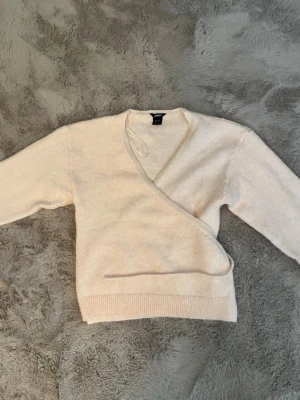 Beige omlottstickad tröja Lindex - Säljer en beige stickad tröja från Lindex i omlottmodell. Tröjan har v-ringning och är helt oanvänd.