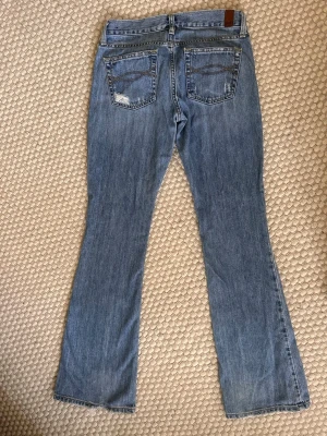 Raka lågmidjade jeans  - Svinsnygga blå raka, lågmidjade jeans från abercrombie and fitch. Köpta på second hand men tyvärr för små för mig. Bra skick och inga defekter.  Storlek 00S, motsvarar en XXS (23-24), midjemått ca 58-61cm) passar mig i längd som är 162cm 