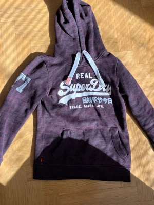 Vinröd Superdry hoodie - Snygg hoodie från Superdry i vinrött. Skitsnygg inför sommaren. Använd ett fåtal gånger. Hör av er vid frågor. Har en lite tajt passform