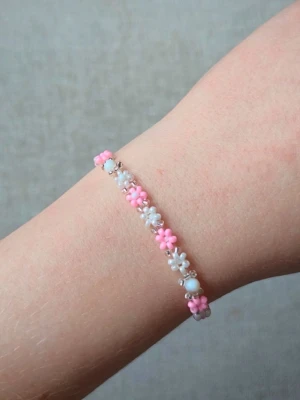 Blomarmband i Miyuki pärlor med äkta pärlemor - Handgjort armband med små blommor i rosa och vitt, gjort av Miyuki seed beads och detaljer i äkta pärlemor som ger ett mjukt och elegant skimmer.  Ett fint och feminint smycke som passar både till vardags och som present.  • Justerbar storlek • Material: Miyuki pärlor & äkta pärlemor • Färger: rosa, vit & silverdetaljer • Handgjord  Ett unikt armband med romantisk och somrig känsla 🌸