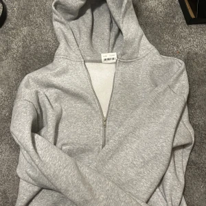Ljusgrå zip hoodie basic, lucid blanks  - En stilren ljusgrå hoodie med dragkedja från H&M. Hoodien har en klassisk huva, två fickor framtill och ribbade muddar vid ärmslut och nederkant. Tillverkad i mjukt sweatshirtmaterial som är perfekt för en avslappnad look.