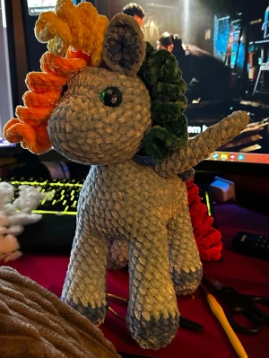 Virkad regnbågsponny mjukisdjur - Handgjord virkad enhörning i mjukt garn med ljusblå kropp och regnbågsfärgad man och svans, vingar. Ögonen är dekorerade med gröna knappar. Perfekt som dekoration eller present till någon som gillar färgglada och unika mjukisdjur. Virkad av mig. 