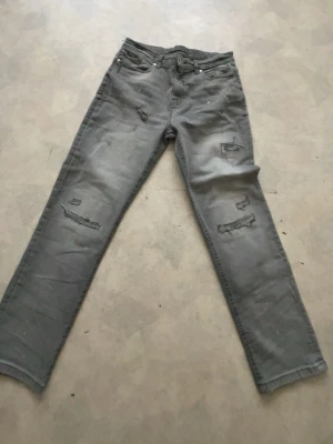 Grå slitna jeans från Supply & Demand - Säljer ett par grå jeans från Supply & Demand de passar 13-15 åringar och är helt nya