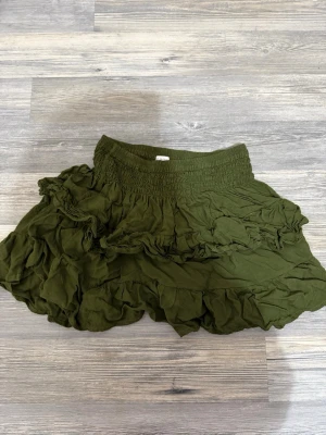 Olivgrön volangkjol från Kroatien - Supersöt olivgrön kjol med volanger. Kjolen har bred resår i midjan och flera lager med rynkade detaljer som ger en bohemisk och avslappnad look. Perfekt att styla med en enkel topp eller stickad tröja. Köpt i Kroatien på en resa o använd 1-2 gånger (egna bilder) skriv till mig vid frågor💕💕