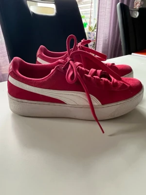 Rosa  Puma sneakers med platåsula - Snygga rosa sneakers från Puma med vit platåsula och klassisk vit sidostrip. Ovandelen är i mockaliknande material och skorna har rosa skosnören.. Perfekta för dig som vill sticka ut med färg och stil.
