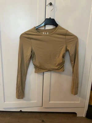 Beige croppad långärmad träningströja SXS - Säljer en beige croppad träningströja från SXS med långa ärmar och rund halsringning. Tillverkad i ett stretchigt syntetmaterial som sitter snyggt och bekvämt. Toppen säljs pga att den tyvärr knappast kommit till användning då jag känner att jag inte riktigt trivs i croppade tröjor. Säljs för 100kr då jag behöver plats i garderoben. Pris kan diskuteras. OBS! Köparen står för frakt.