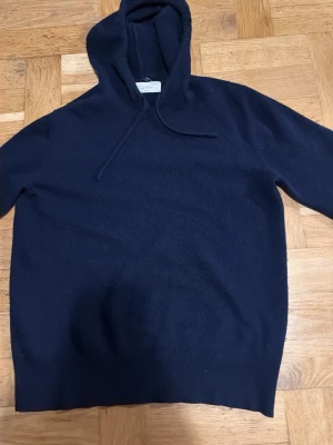 Mörkblå hoodie från Sayless - Mysig mörkblå hoodie från Sayless med klassisk huva och dragsko. Tillverkad i ett mjukt material som känns skönt mot huden. Perfekt för dig som gillar en enkel och stilren look. Passar till det mesta och är lätt att matcha med andra plagg.