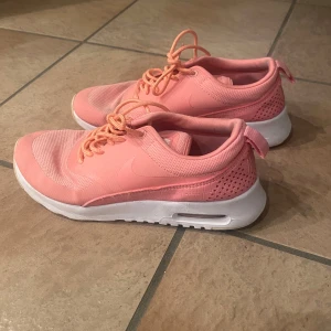 Nike rosa sneakers med vit sula - Snygga rosa sneakers från Nike med vit sula och diskret logga på sidan. Skorna har meshdetaljer för extra ventilation och klassisk snörning. Perfekta för dig som vill ha en sportig och trendig look. Finns tecken på användning 