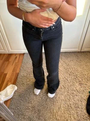 Svarta bootcut jeans  - Säljer ett par svarta bootcut jeans med hög midja och klassiska fem fickor. Jeansen har en snygg tvätt och är tillverkade i ett stretchigt denimtyg som sitter bekvämt. Perfekta för dig som gillar en tidlös och trendig look.