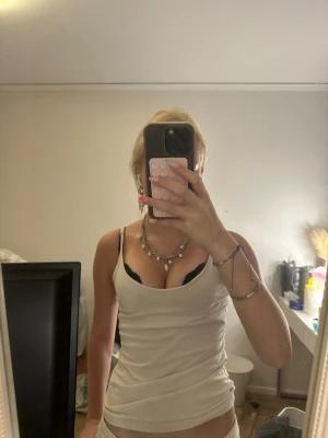 Vitt linne - Säljer en vit ribbad linnetopp med smala axelband och figurnära passform. Toppen är ärmlös och har en enkel, clean look som är lätt att styla till olika outfits. Materialet känns mjukt och stretchigt.