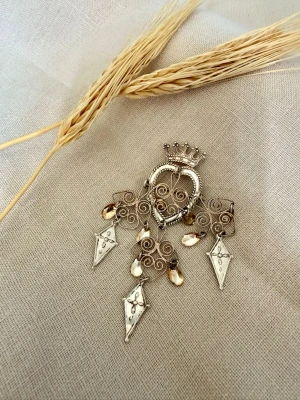 Antik traditionell norsk brosch i silver. Knut Andreas Rasmussen  - Magisk traditionell norsk söljebrosch i filigranarbete, stämplad 830S. Tillverkad av Knut Andreas Rasmussen, en av Norges mest välkända silversmeder. Dekorerad med hjärtform, krona och rörliga hängen.  Fint vintage-skick med fungerande nål och lås. Se bilder för skick och detaljer.  Ett vackert samlarföremål eller ett klassiskt smycke till folkdräkt eller bunad.