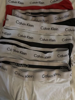 Calvin Klein kalsonger i flera färger - Säljer ett flerpack kalsonger från Calvin Klein i färgerna röd, svart och vit. Klassisk design med bred resår och logga runt midjan. Materialet är mjukt och stretchigt, perfekt för vardagskomfort. Snygga och stilrena underkläder som passar till allt. 