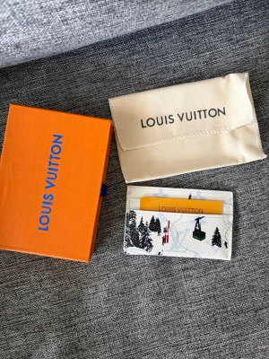 Lv korthållare - Säljer en exklusiv vit korthållare från Louis Vuitton med vinterinspirerat tryck av skidåkare, liftar och granar. Tillverkad i tåligt läder med klassiskt monogrammönster i bakgrunden. Kommer med original ask och dustbag.