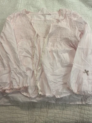 Ljusrosa blus från Odd Molly - Supersöt ljusrosa blus från Odd Molly med smockdetaljer upptill, knytband framtill och broderad detalj på ärmen. Säljer då den aldrig kommer till användning, pris kan diskuteras.